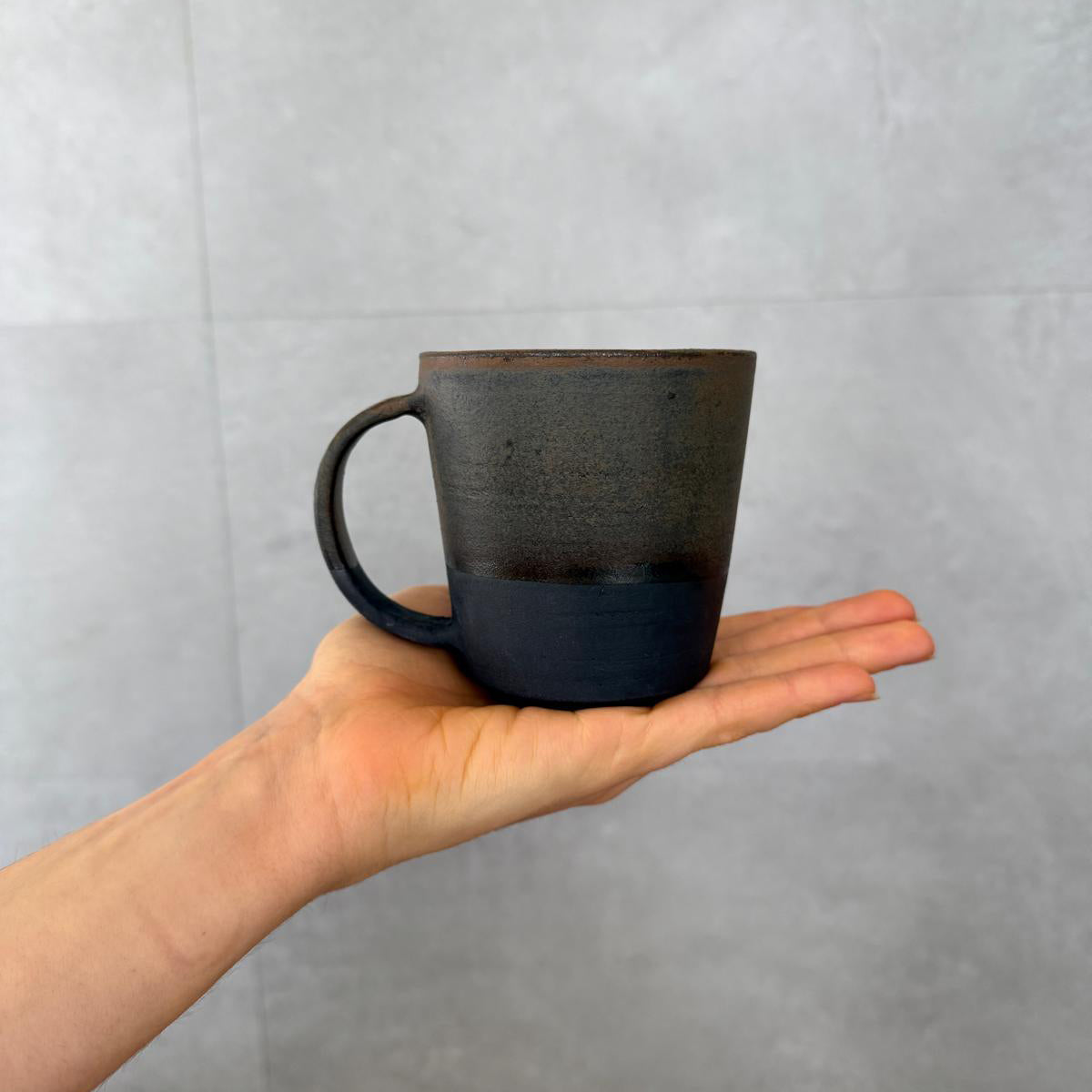 Handgedrehte AREIA Negra Kaffeetassen mit Henkel auf Handfläche, matte Oberfläche, FRANZART Keramik