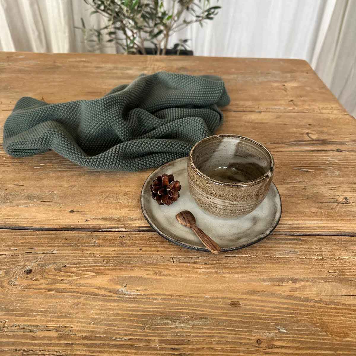 Becherset aus schwarzem Steinzeug mit braun-weißem Becher und schlicht weiß glasiertem Teller