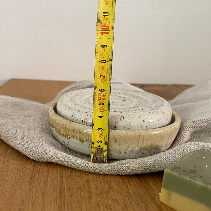 Runde Keramikseifenschale mit Löchern für das Tropfwasser und einer Auffangschale, weißer Steinzeugton mit Spots.
