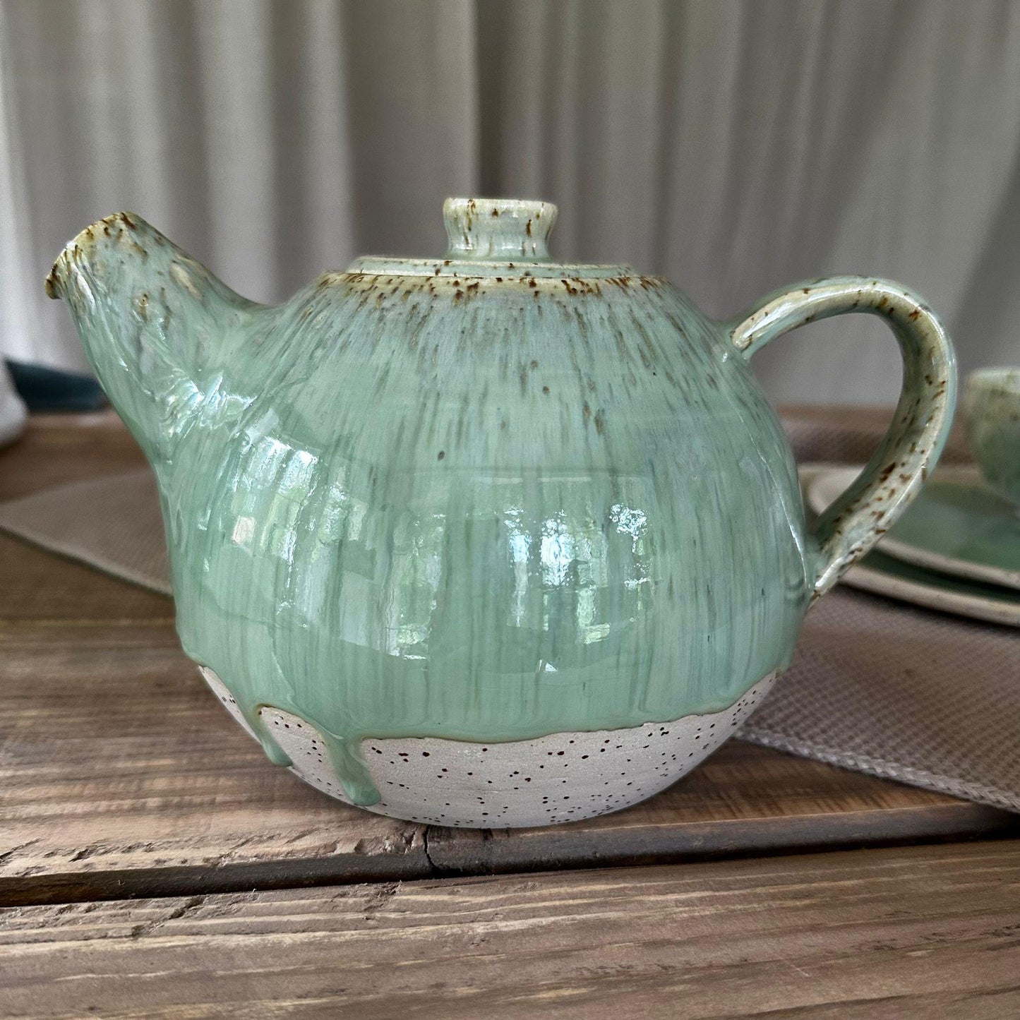 Teekanne aus Steinzeugton mit Spots. Grüne, glänzene Glasur, bauchige Form.