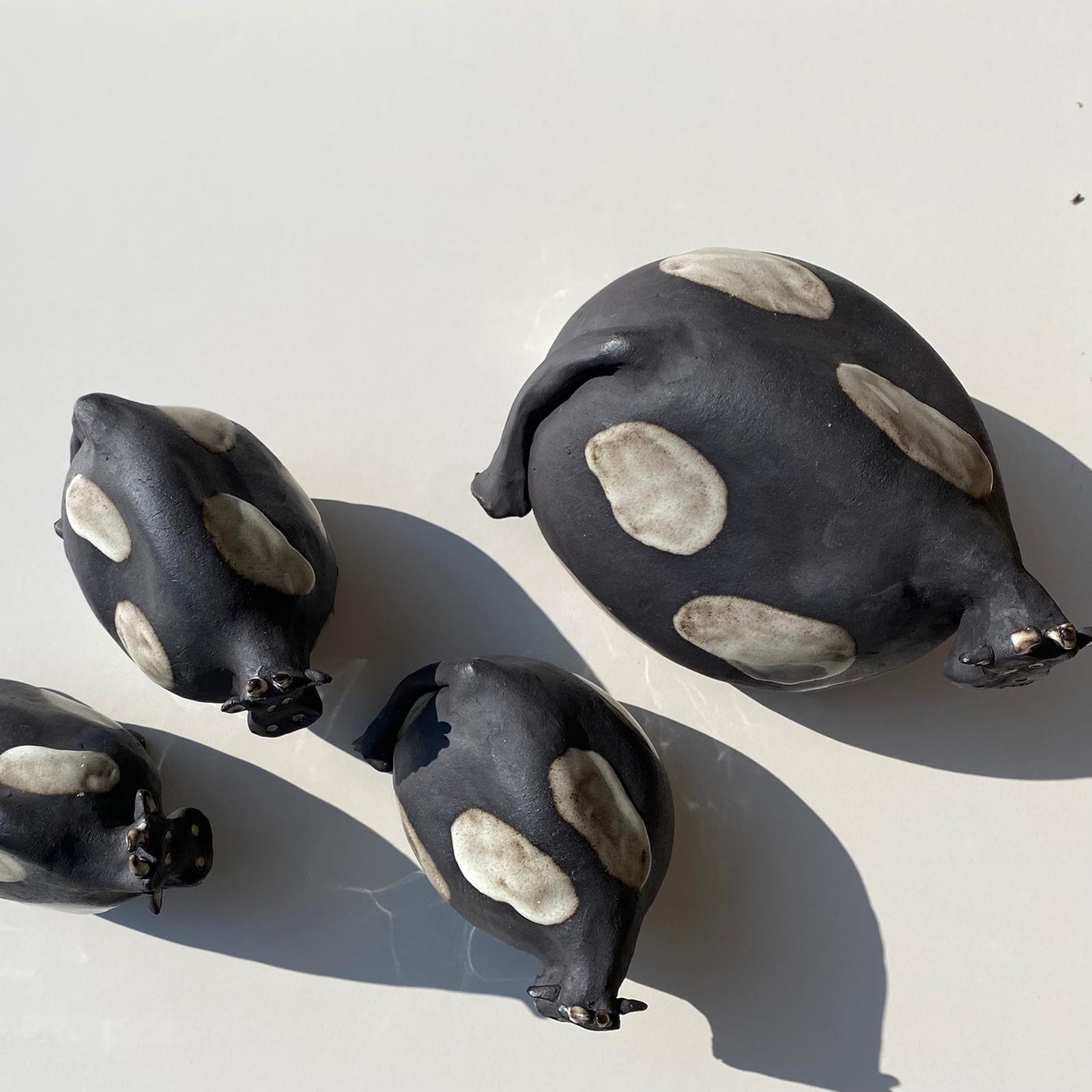 Schwarz-weiß gefleckte Kühe aus Keramik von oben, schwarzer Steinzeugton.