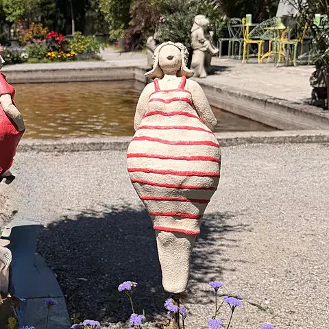 Keramikfigur Badedame mit rot-weiß gestreiftem Badeanzug und Hut, Rückansicht im Blumenbeet