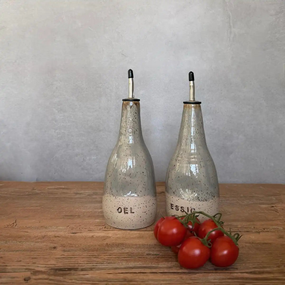 Zwei BOHEMIAN Grey Keramik Öl- & Essigspender auf Holztisch mit frischen Tomaten.