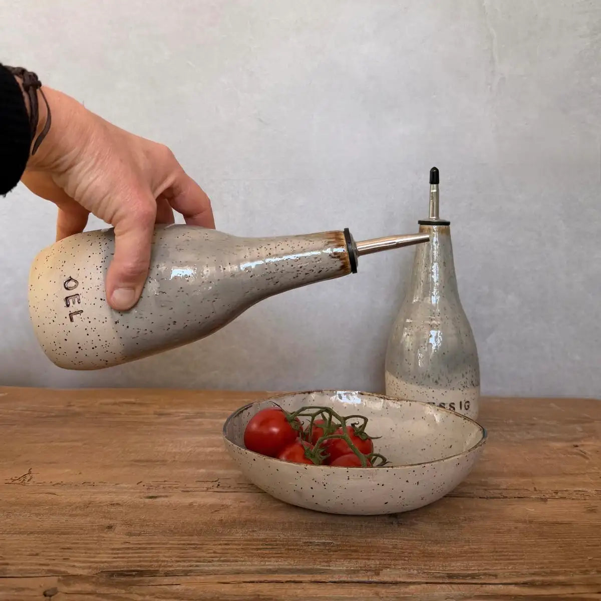 BOHEMIAN Grey Keramik Öl- & Essigspender beim Servieren von Öl über frischen Tomaten auf einem Holztisch.