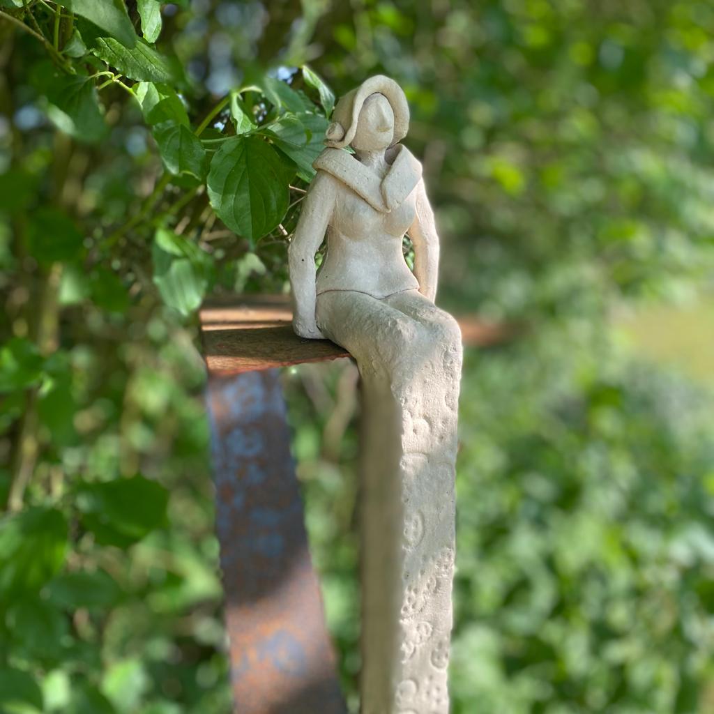 Sitzende Keramikdame aus weißem Steinzeugton sitzt auf einem Ständer aus Cortenstahl
