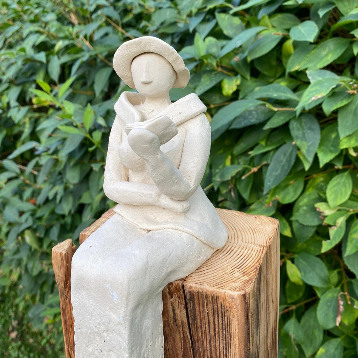 Sitzende Keramikdame aus weißem Steinzeugton liest ein Buch und sitzt auf einem Ständer aus Antikholz