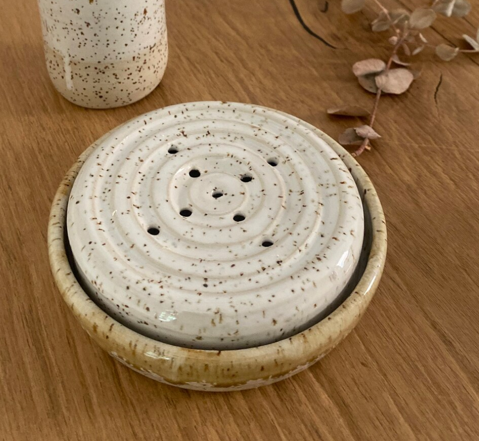 Runde Keramikseifenschale mit Löchern für das Tropfwasser und einer Auffangschale, weißer Steinzeugton mit Spots. 