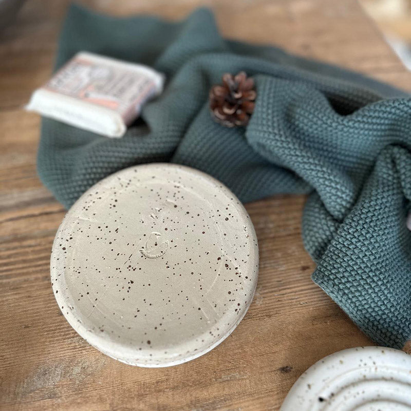 Detailansicht weiße runde Seifenablage mit konzentrischen Rillen und Sprenkelglasur, Ansicht von unten