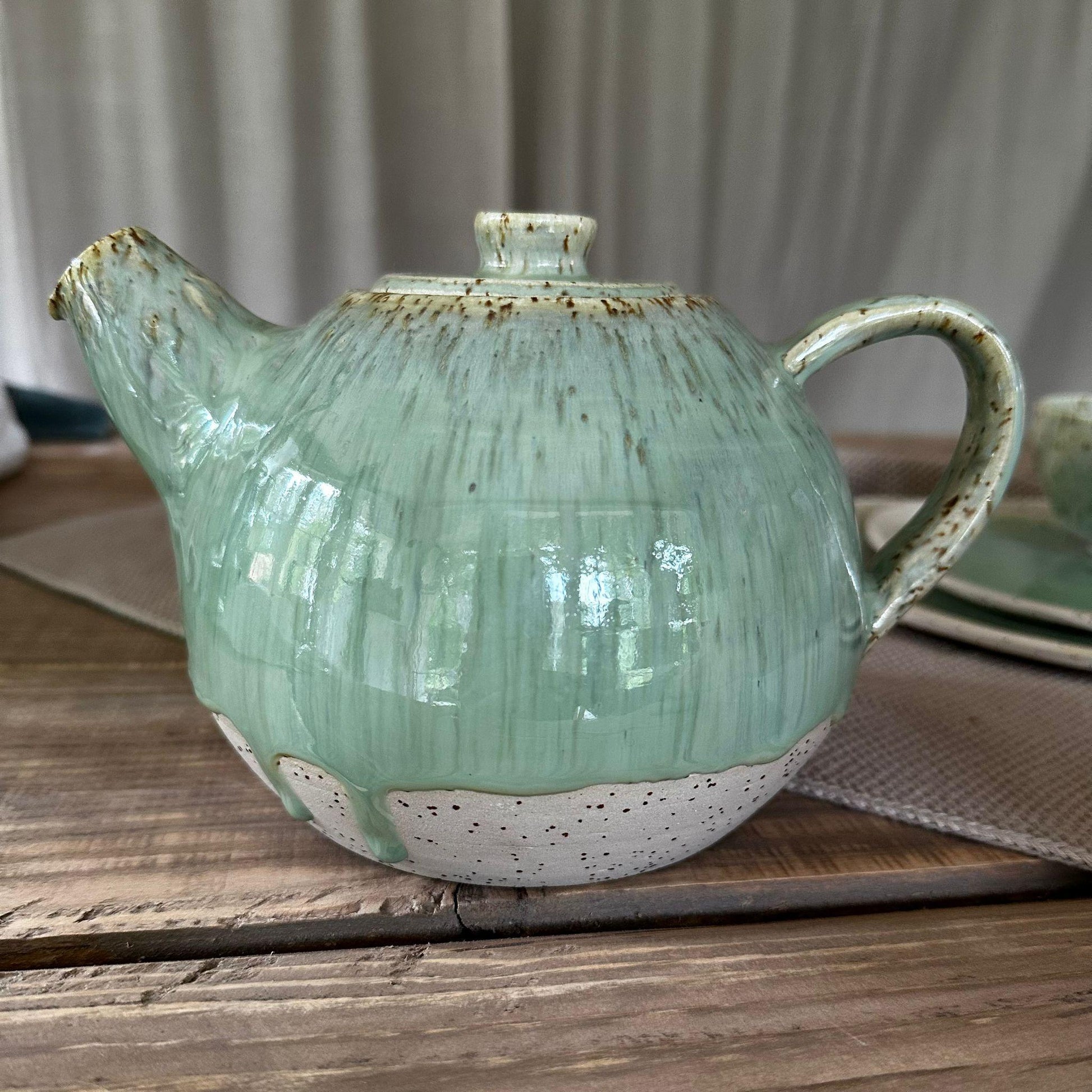 Teekanne aus Steinzeugton mit Spots. Grüne, glänzene Glasur, bauchige Form.
