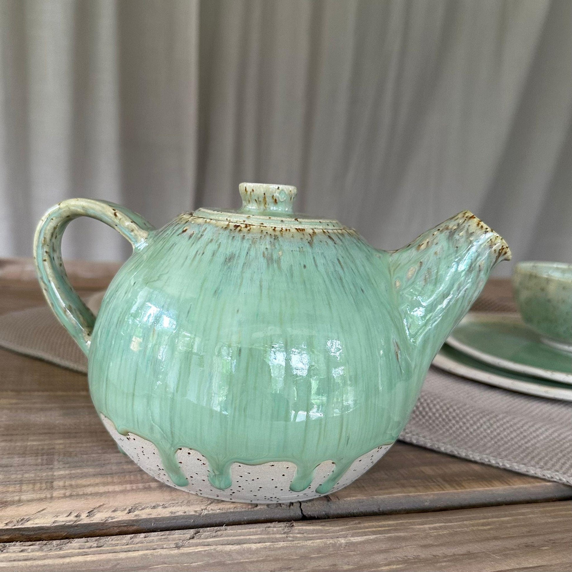 Teekanne aus Steinzeugton mit Spots. Grüne, glänzene Glasur, bauchige Form.